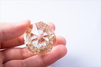 Hand holding a transparent diamond on a white background