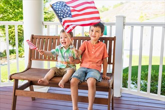 Young mixed-race chinese and caucasian brothers playing with american flags