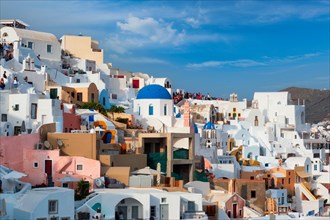 Tourist crowd and queue to a famous viewpoint with greek orthodox church blue dome in Oia Village