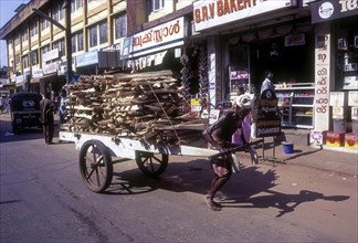 An old man pulling the cart with fire wood in Kozhikode