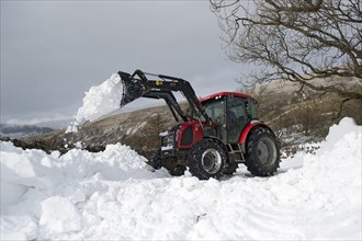 Zetor tractor with loader clears snow from blocked country road after snowstorm