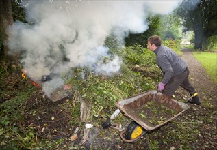 Gardener burning garden rubbish on bonfire