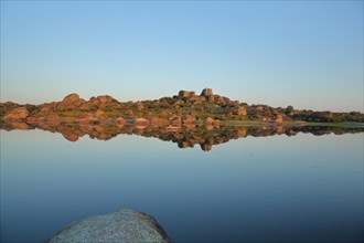 Reflection of rock formations in lakescape at calm in Los Barruecos