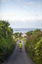 Woman in yellow walking Irish road down to Renvyle beach