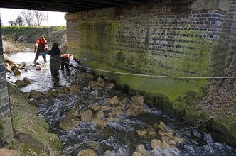 Men building fish pass underneath bridge on river