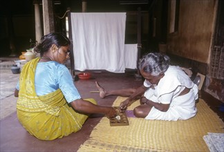 Two woman sitting on the floor and playing Pallanguzhi in Chettinad