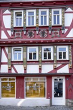 Historic half-timbered house with colourfully painted and carved wooden beams and family coat of arms