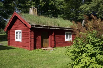 Red log cabin with turf roof