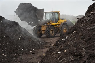 Volvo loader turning green compost waste for aeration at municipal waste site