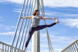 Extended hand to big toe yoga pose performed on a bridge
