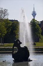The Jroener Jong fountain in the Hofgarten with the Rhine Tower in the background