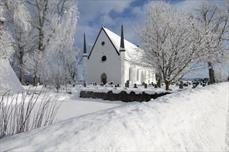 View of snow covered church and graveyard
