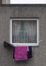 Laundry rack hanging out of the window on the first floor of a dreary apartment block