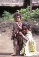 Belta kurumba tribal girl sitting with her brother in Mudumalai