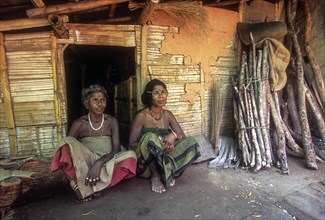Muduga tribal women sitting in front of their hut