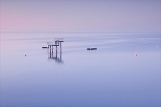 Rosa-violette Abendstimmung ueber dem Bodensee mit Blick zum Sprungturm und den Flossen der Freibadanlage Horn inmitten des Sees