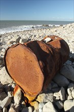 Rusty metal oil drum washed up on beach