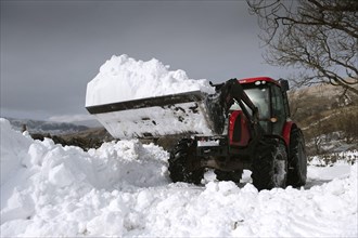 Zetor tractor with loader clears snow from blocked country road after snowstorm