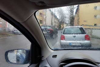 Blick aus dem Auto durch eine regennasse Scheibe mit unklarer Sicht auf den Verkehr