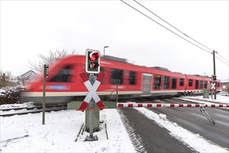 Passing train at a level crossing with barriers in sleet