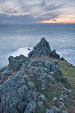 View of craggy basalt rocks on coastal headland at sunset