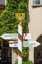 International signpost and coat of arms of Isny in front of the town hall