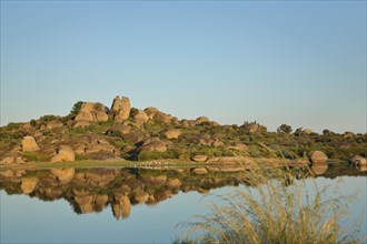 Reflection of rock formations with tufts of grass and lakescape in Los Barruecos