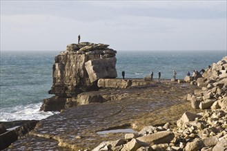 People climbing on large rock at coastal headland