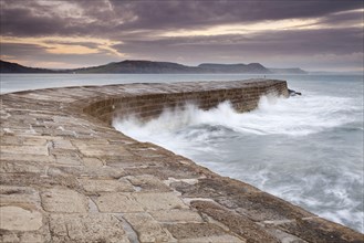 View of the harbour wall with the waves breaking at sunrise