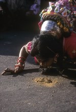 A folk dancer lifting the needle from the floor by the eye lashes during Pongal festival celebration at Madurai