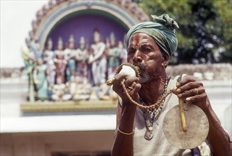 Sadhu blowing conch standing infornt of Nataraja temple