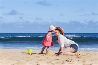 Mother and daughter kissing on the beach