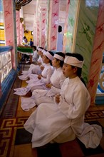Caodaist disciples sitting on balcony during ceremony