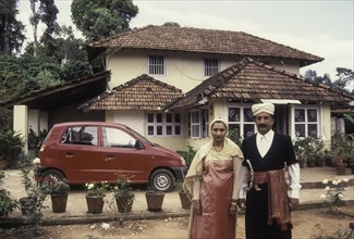 Kodava couple in traditional house in front of their house