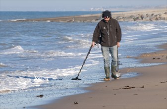 Man using metal detector on beach