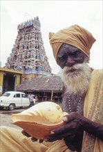 Sadhu holding conch standing infornt of Nataraja temple in Perur near Coimbatore