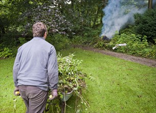 Gardener burning garden rubbish on bonfire