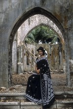 A woman standing in front of overgrown destroyed church on Ross Island