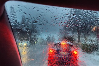 Blick aus dem Auto durch eine regennasse Scheibe mit unklarer Sicht auf den Verkehr am Abend