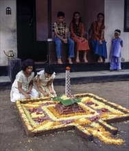 Girls doing floral decoration or pookalam during Onam festival in Kodungallur