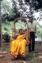 Mother sitting in hanging cane chair and her son standing nearby at Singara