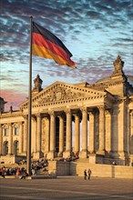 Main entrance of the Reichstag in the late evening sun with waiting tourists