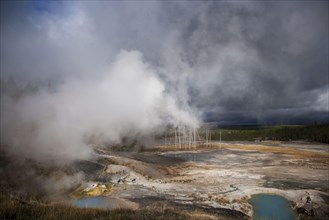 View of hot springs with steam and approaching storm clouds