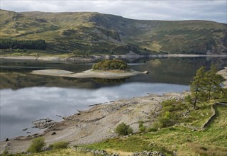 View of an upland reservoir with low water level and remains of a submerged village exposed after a dry summer