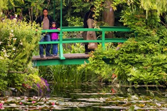Japanese bridge over lily pond with visitors