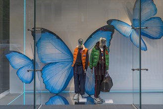 Shop window with fashionable mannequins and large paper butterflies