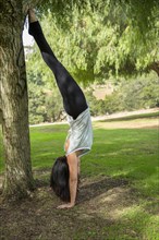 A woman performing a headstand in Balboa Park