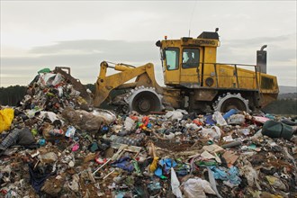 Compactor moving rubbish on landfill tip