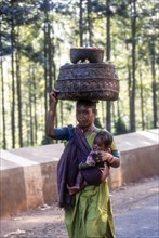 Tribal woman carrying her daughter on hip and carrying vegetable basket on head in Araku Valley near Vishakapatnam