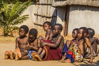 Children watch with interest at traditional customs in real African village